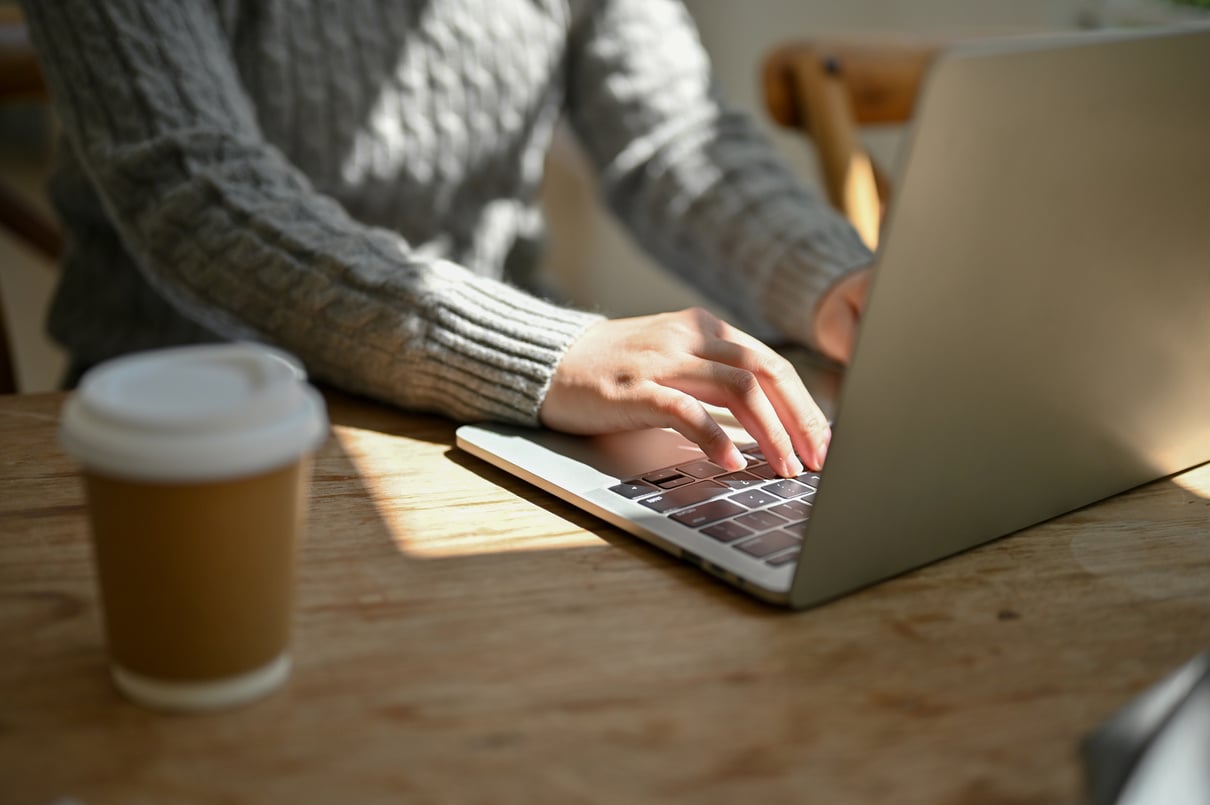 Close-up image of a female freelancer responding to emails, typing on her laptop keyboard